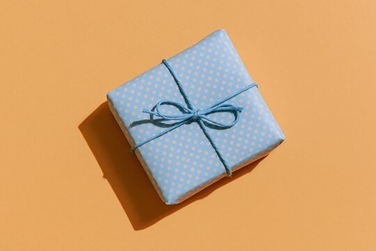 The Polka Dot Gift Box Wrapped with Blue Twine on Orange Background