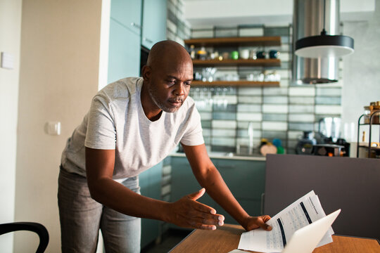 Man discussing bills on video call in kitchen