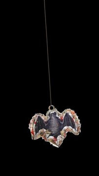 An animated Halloween themed hanging element in a paper-collage style that gently sways on a loop and features spooky ephemera details.
