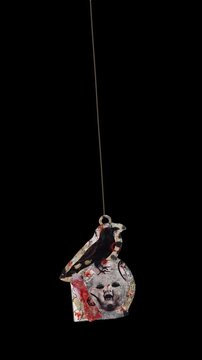 An animated Halloween themed hanging element in a paper-collage style that gently sways on a loop and features spooky ephemera details.
