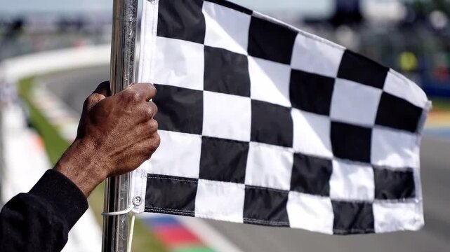 Hand waves checkered flag at racetrack. Finish line, motorsport competition. Racing event and victory signal. Auto racing, speed and sport.