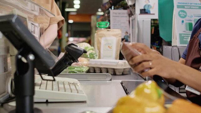 Side view shot of female cashier scanning groceries with barcode scanner at supermarket checkout counter. Perfect for retail technology, grocery business, and customer service promotional videos