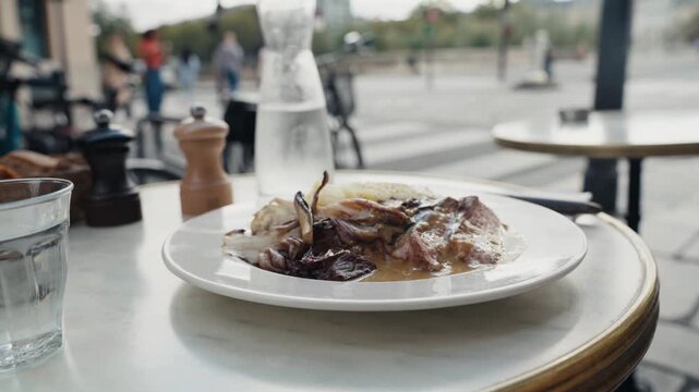 Waiter serving a plate of meat and vegetables at an outdoor parisian cafe