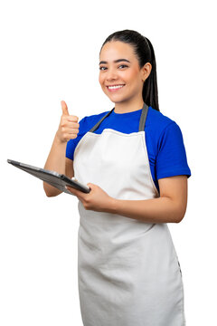 Happy latina worker in apron holding tablet and showing thumbs up gesture