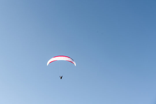 View of a paraglider soaring through a clear blue sky in Slovakia.