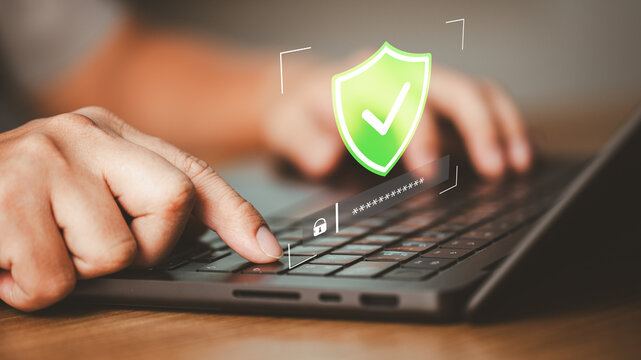 Close-up of person typing on laptop keyboard with digital security shield and password interface. Concept of cybersecurity, data protection and secure login information technology system