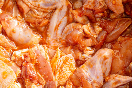 Raw Marinated Chicken Meat and Wings Background Close Up,Full frame macro photo of fresh raw chicken meat pieces and wings marinated in savory seasoning sauce and spices, ideal for cooking recipes, 