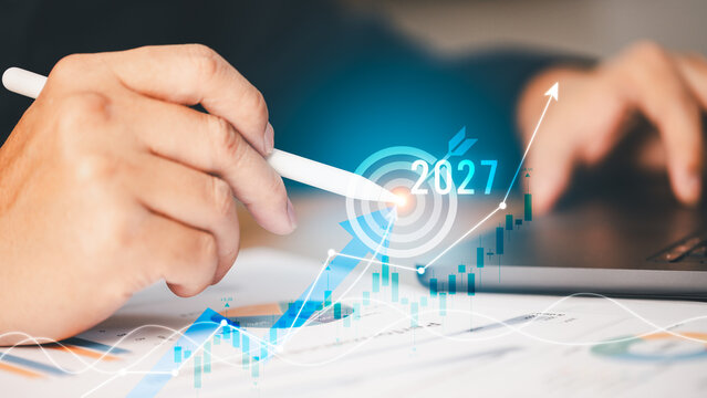 Close-up person pointing stylus pen digital target 2027 financial growth chart data laptop. Concept business strategy corporate success investment planning future economic vision marketing