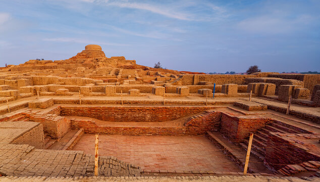 View of the ancient brick ruins of the Grand Bath at the archaeological site of Mohenjo-daro with surrounding structures under a clear sky in Mohenjo-daro, Sindh, Pakistan.