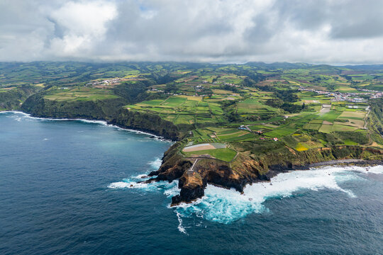 Aerial view of a rural peninsula with patchwork farmland, Atlantic Ocean on both sides. Agricultural coastal landscape of Sao Miguel Island