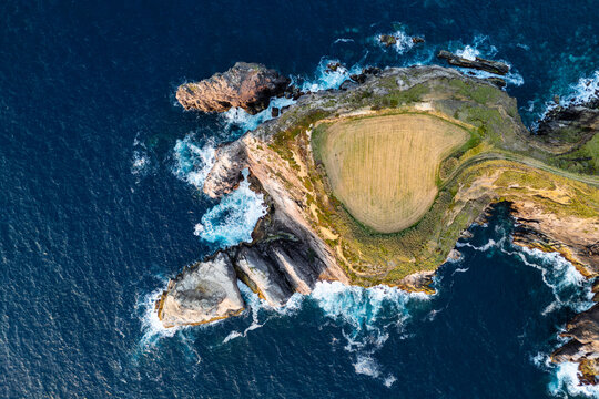 Rocky headland and sea stacks on Sao Miguel, Azores, Portugal. Coastal farmland and jagged cliffs surrounded by Atlantic Ocean