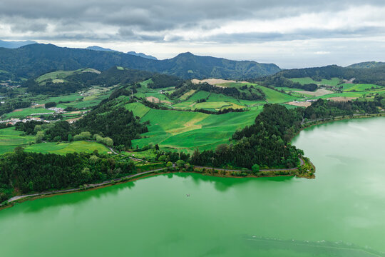 Aerial view of Furnas crater lake with forest, hills and village, Furnas region scenic travel landscape, Sao Miguel Azores