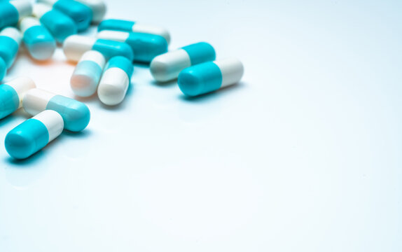 Blue-white capsule pills on white background. Antibiotic drug resistance concept. Capsule pills sampling in pharmaceutical industry. Antimicrobail medicine. Pharmacy product. Medication for infection.