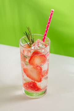 Fresh strawberry infused water with herbs on green background with copy space