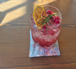 Sparkling red berry drink with dried lemon and rosemary garnish © kreative