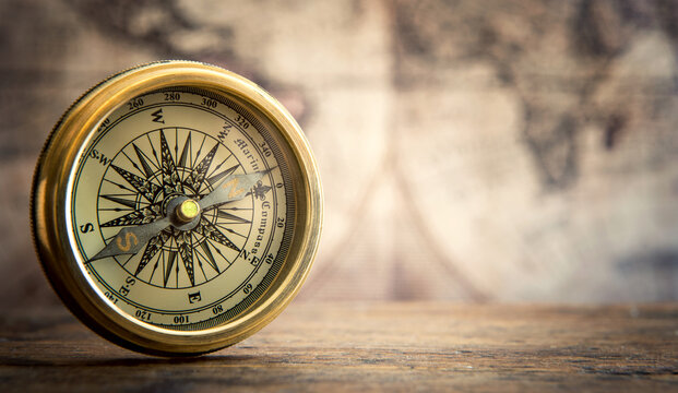 Old compass on vintage map background. Adventure stories background. Retro style.