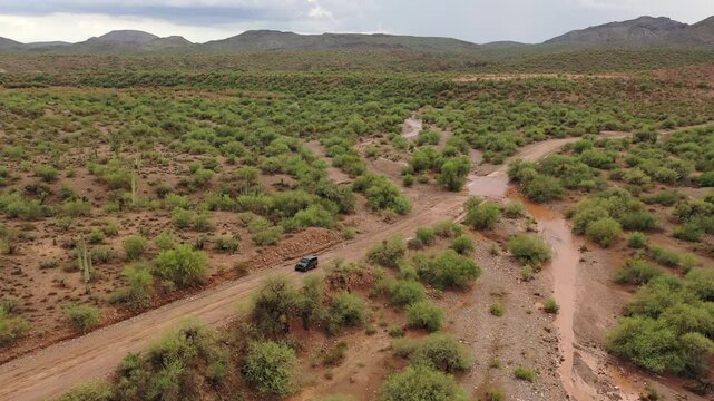 SUV driving on a rugged dirt road in a desert landscape