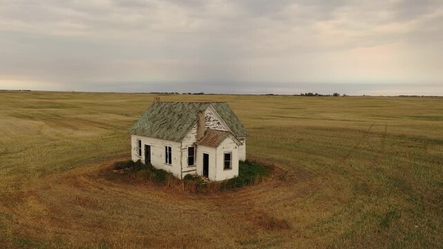 Abandoned farmhouse in vast rural prairie landscape