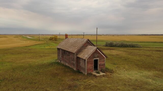 Abandoned wooden house on rural prairie under cloudy sky