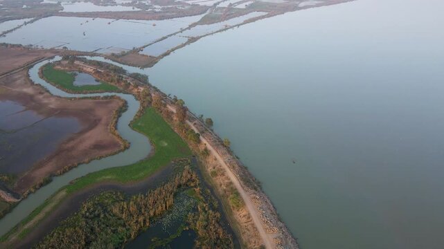 Aerial view of Qadirabad Head Works Bridge spanning the Chenab River with wetlands, green fields, and a dirt road in Wazirabad, Punjab, Pakistan.