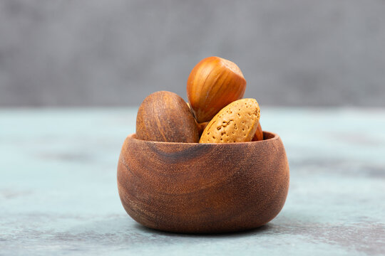 Nuts mixture, hazelnuts, peanuts and almonds in a wooden bowl, healthy food, nutrition, ingredients for baking, protein and antioxidants