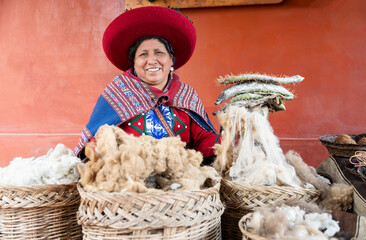 Smiling Peruvian woman with baskets of raw alpaca wool in textile workshop © Dulúapics