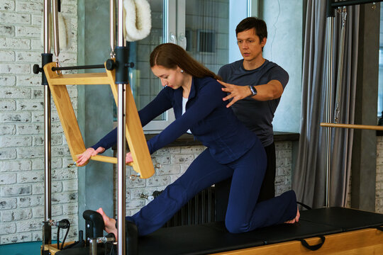Personal trainer stabilizing a kneeling lateral reach - wide view
