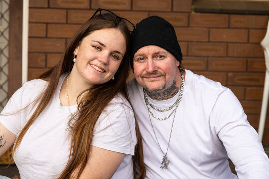 Happy couple sitting closely outside suburban family home
