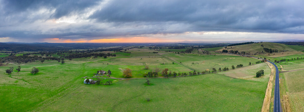 Aerial panorama of a sunset under a heavy cloud over wide green farmland