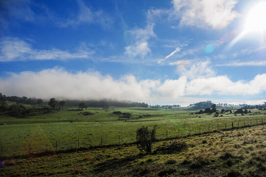 Low cloud drifts across the green field partially veiling the distant hills