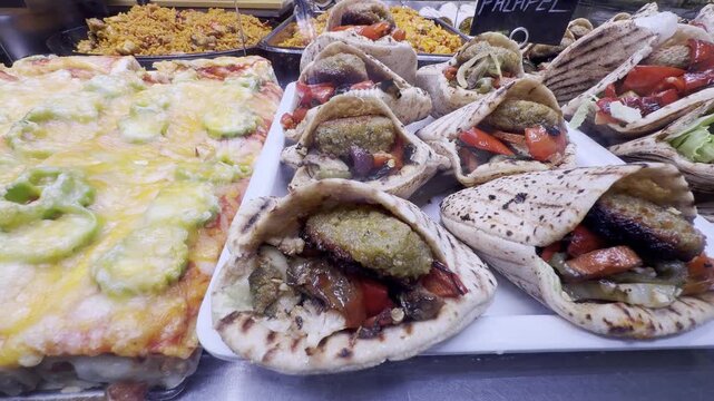 Fresh falafel in pita bread and other ready-to-eat meals displayed at a food market