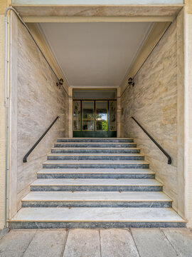 Detailed vertical photo of a 1970s Athenian apartment building marble entrance staircase and recessed doorway in Athens, Greece.
