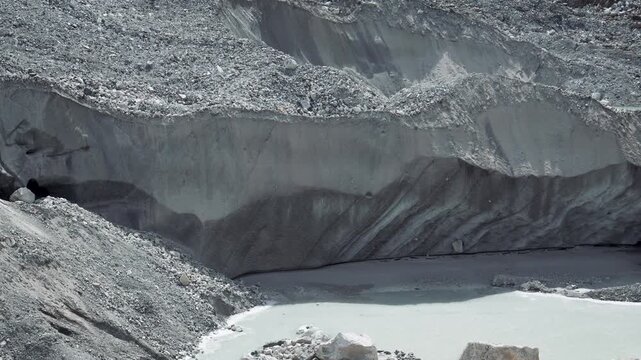Global warming causing the melting of dirty glacier, with ice and rock collapsing into glacial lake, highlighting dramatic effects of climate change on our planet cryosphere. In Nepal himalaya
