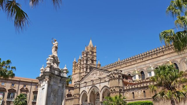 Horizontal video composition featuring the marble Santa Rosalia statue, framed palm foliage, gothic porch arches, and detailed cathedral masonry.