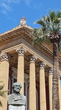 Vertical video composition emphasizing the low-angle height of Teatro Massimo's Corinthian columns and the marble Giuseppe Verdi bust statue.