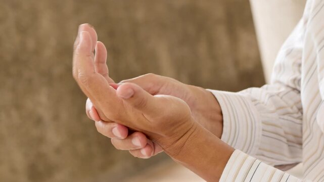 60s old east asian man massaging his hand and finger, home remedy concept, side of hand view