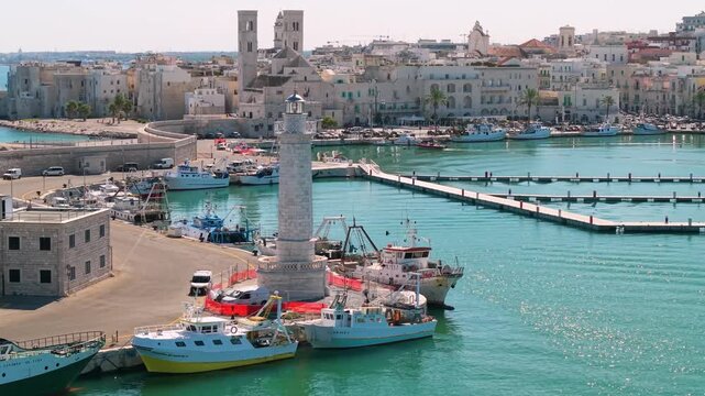 Molfetta Puglia Italy 4K drone video. Close up lighthouse and fishing boats with view on white old town and twin towers cathedral. Authentic coastal towns undiscovered destinations 