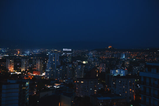 Illuminated city skyline at dark night. Urban cityscape overview with glowing lights