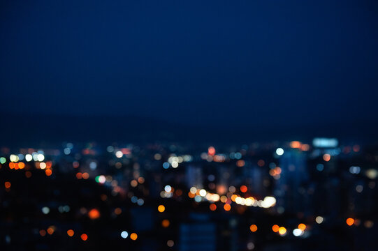Bokeh city lights background at dark night. Blurred urban skyline with glowing circles