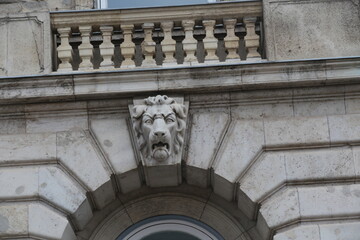 Stone lion head carving on a building facade © Ordódi