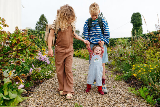 Baby learning how to walk with brother and sister going to school
