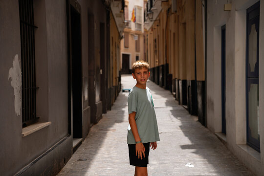 Child Standing In Narrow Old Town Alley In Spain