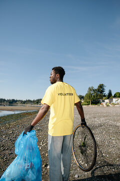 Volunteer beach cleanup: man picking up trash on shoreline