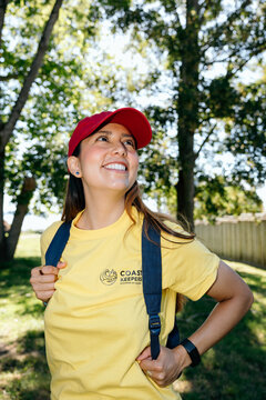 Smiling volunteer in red cap and yellow Coast Keepers shirt