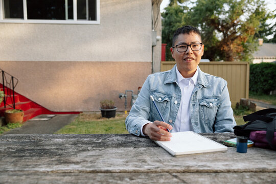 Candid student portrait writing outdoors in backyard with denim