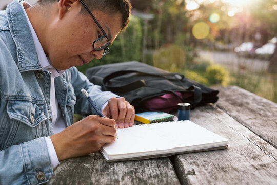 Candid student sketching in park notebook at sunset
