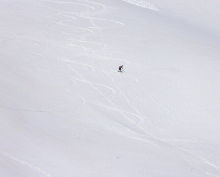View of an alpine skier carving tracks on a vast snow-covered mountain slope in Fjord, More og Romsdal, Norway.