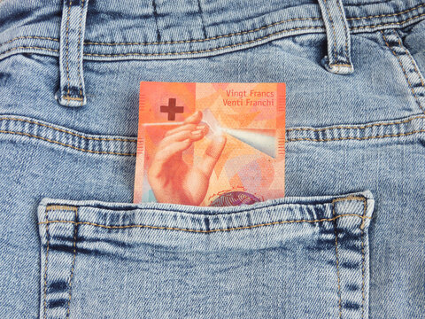 Light prism and hand gesture on 20 Swiss franc banknote in blue denim jeans pocket