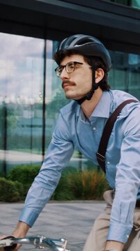 Man rides bicycle forward across glass office plaza in city