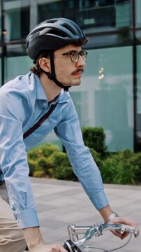 Man pedals bicycle past glass windows in business courtyard